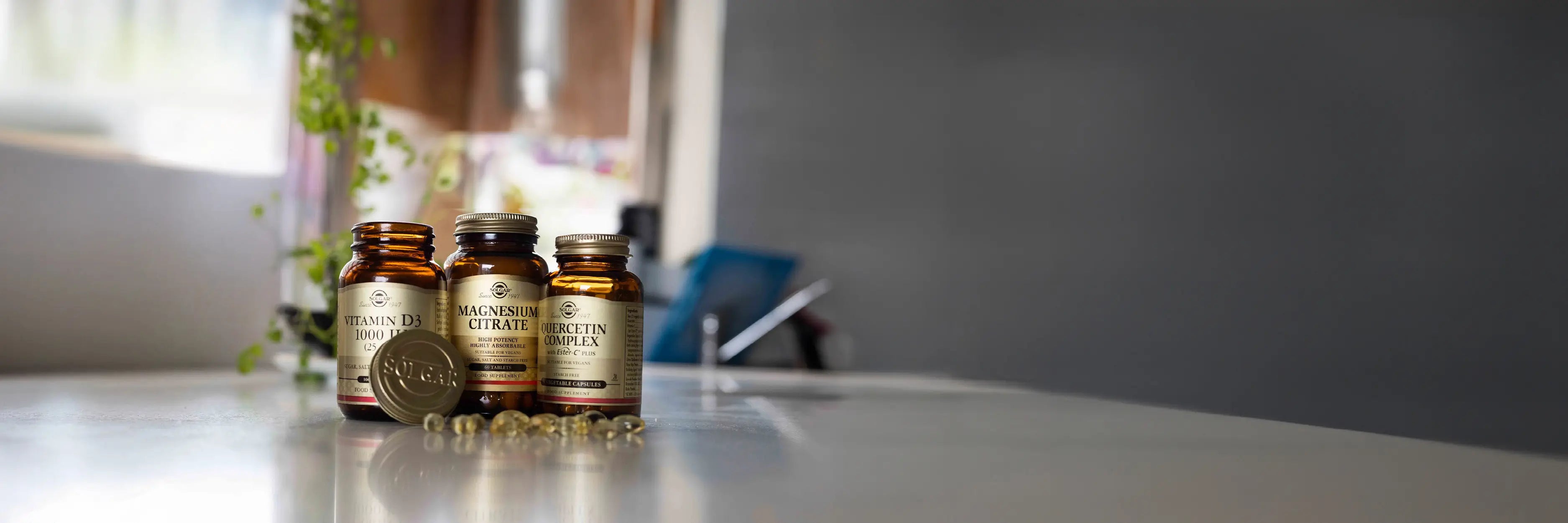 Three Solgar supplement bottles on a grey surface against a blurred background.