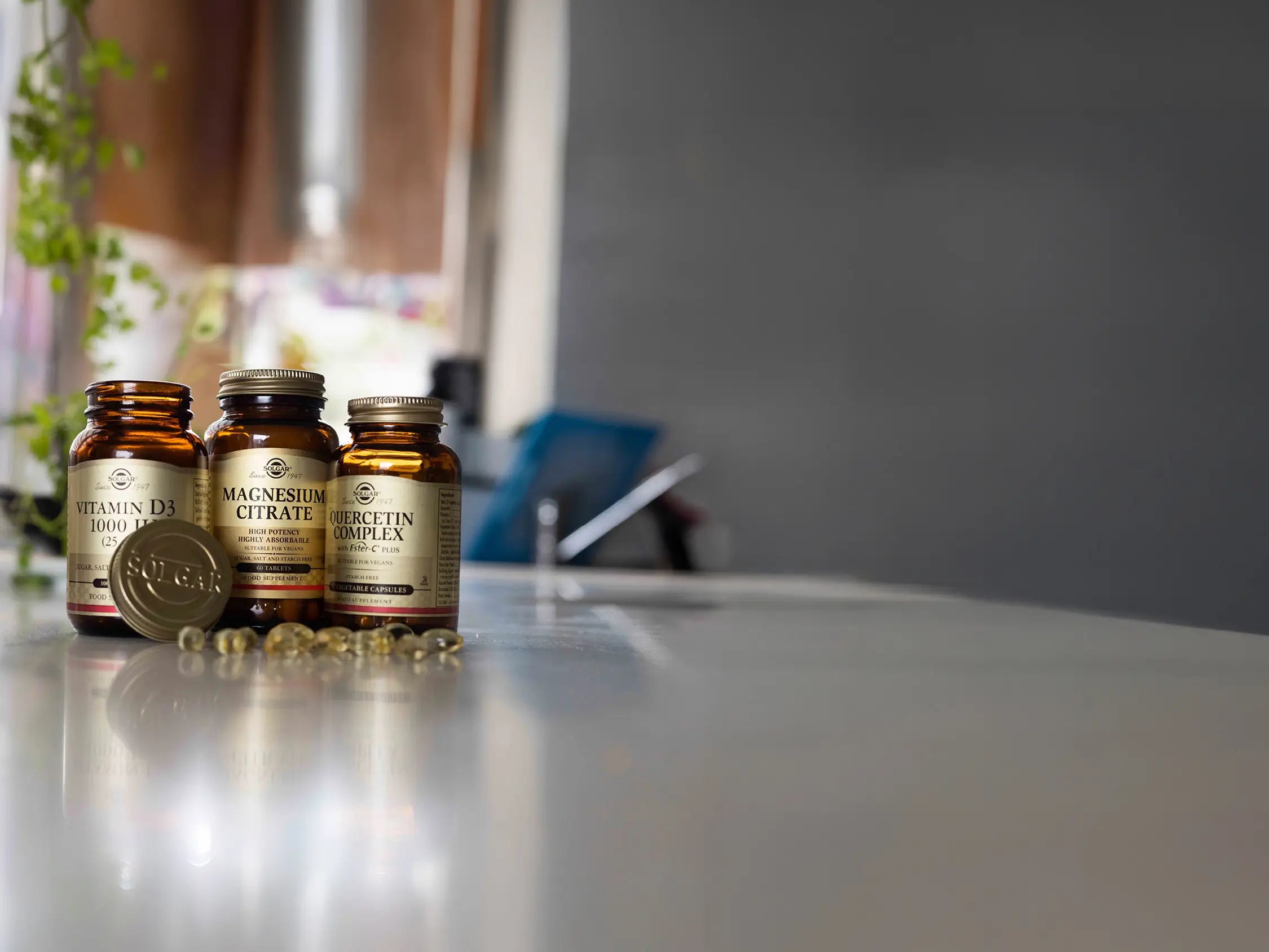 Three Solgar supplement bottles on a grey surface against a blurred background.