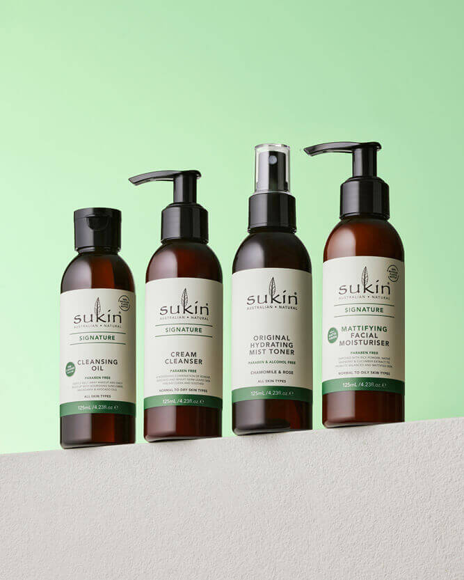 Four Sukin skincare products on a light gray surface with a green background.