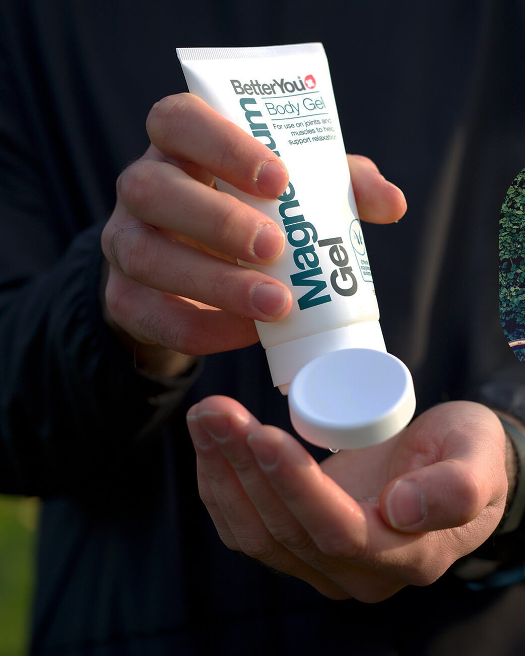 Person holding a tube of BetterYou Magnesium Body Gel outdoors