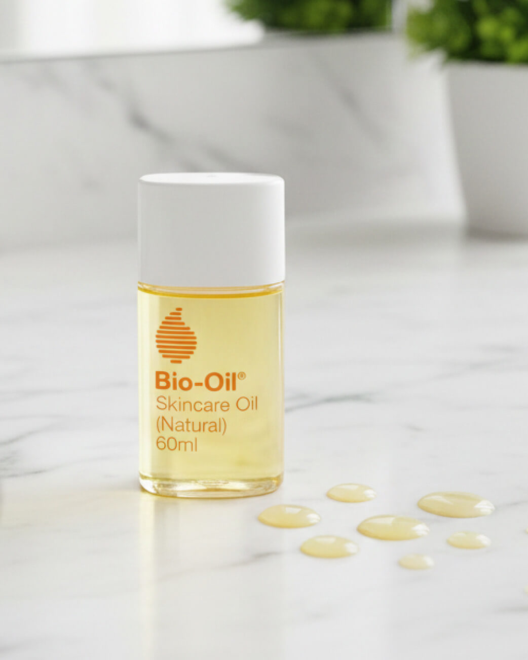 Bio-Oil skincare oil bottle on a light surface with droplets around it.