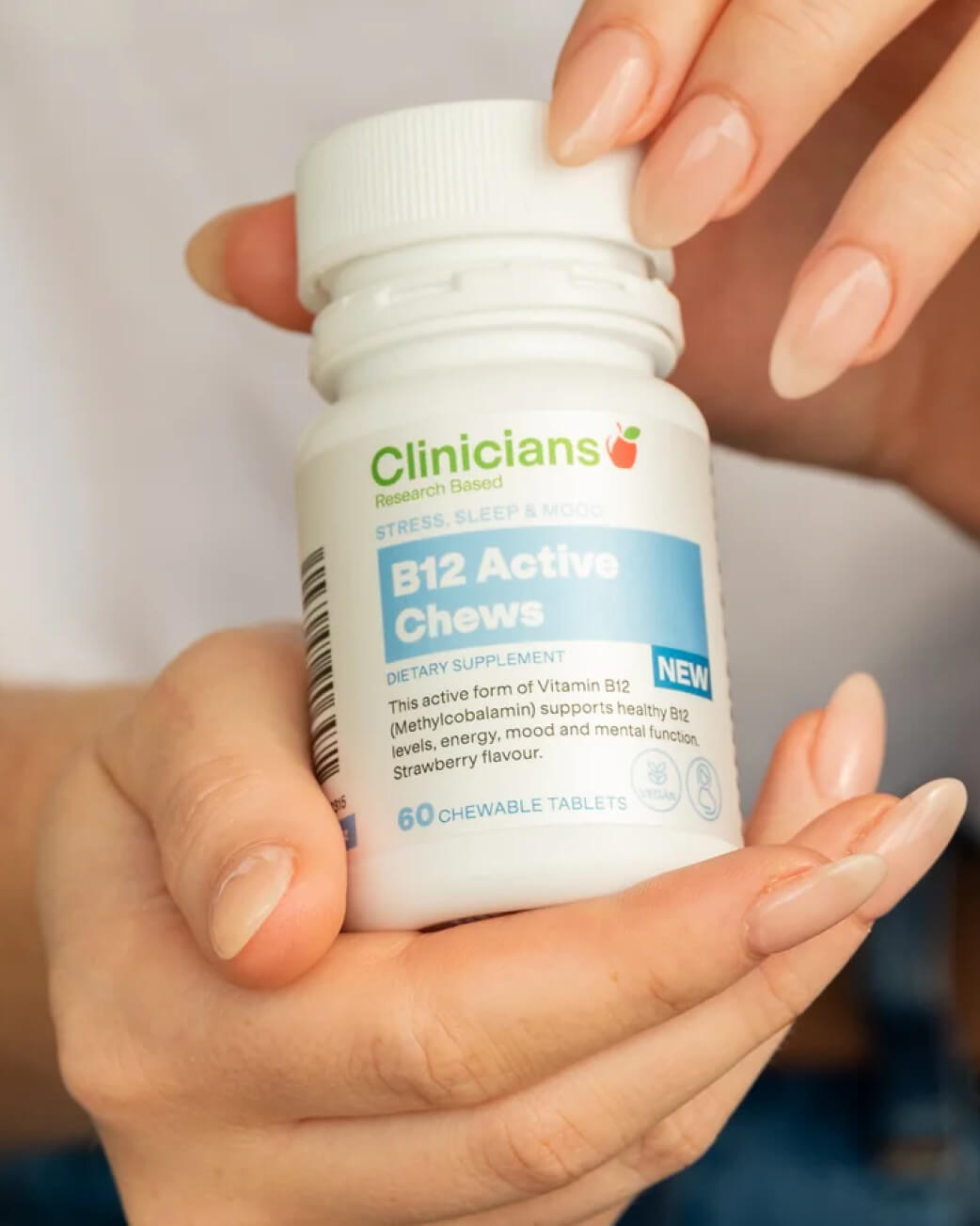 Hand holding a bottle of Clinicians B12 Active Chews supplement.