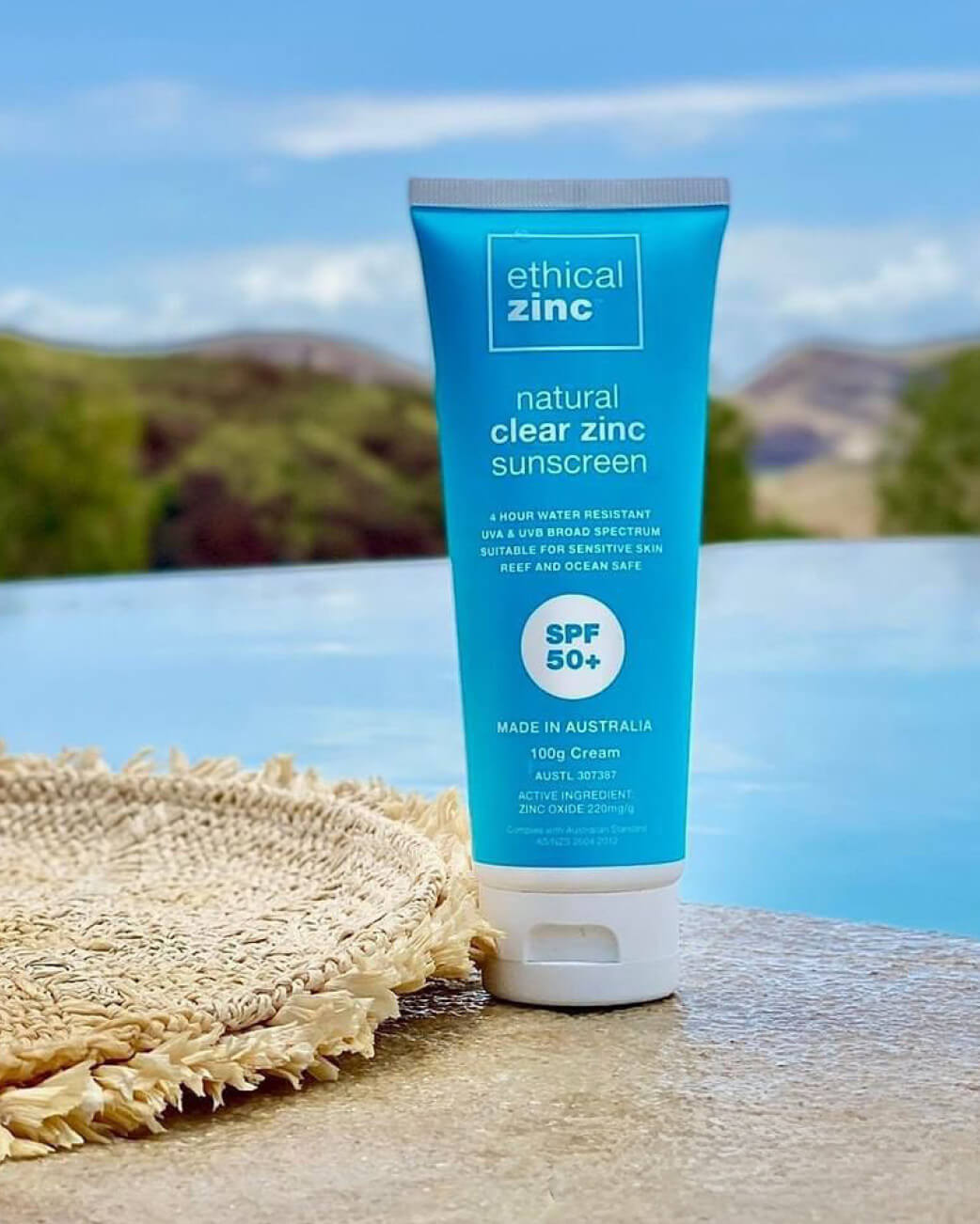 Tube of ethical zinc sunscreen with a scenic background.