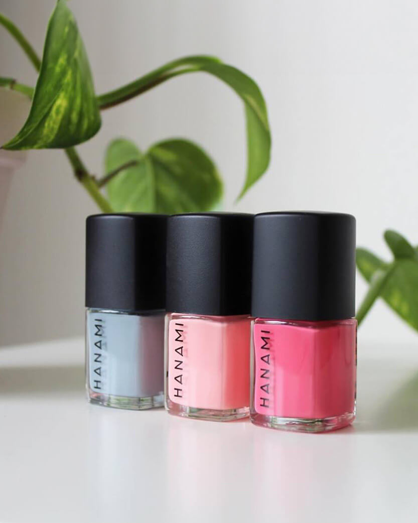 Three lip gloss bottles with black caps on a white surface, featuring the brand 'HANAMI'.