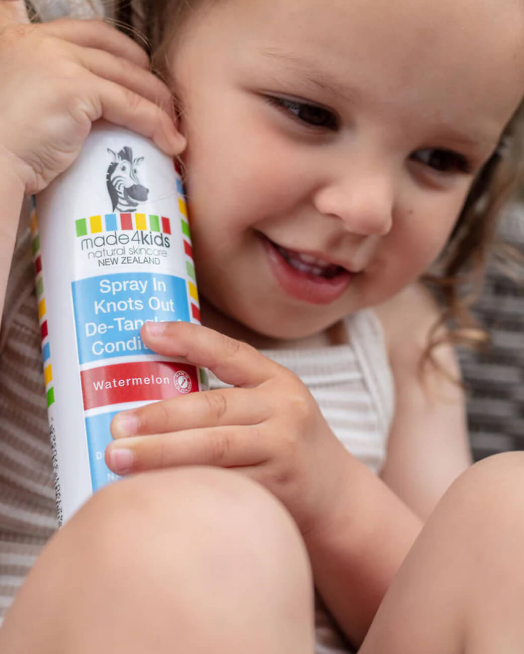 Child holding a bottle of made4kids hair care product.