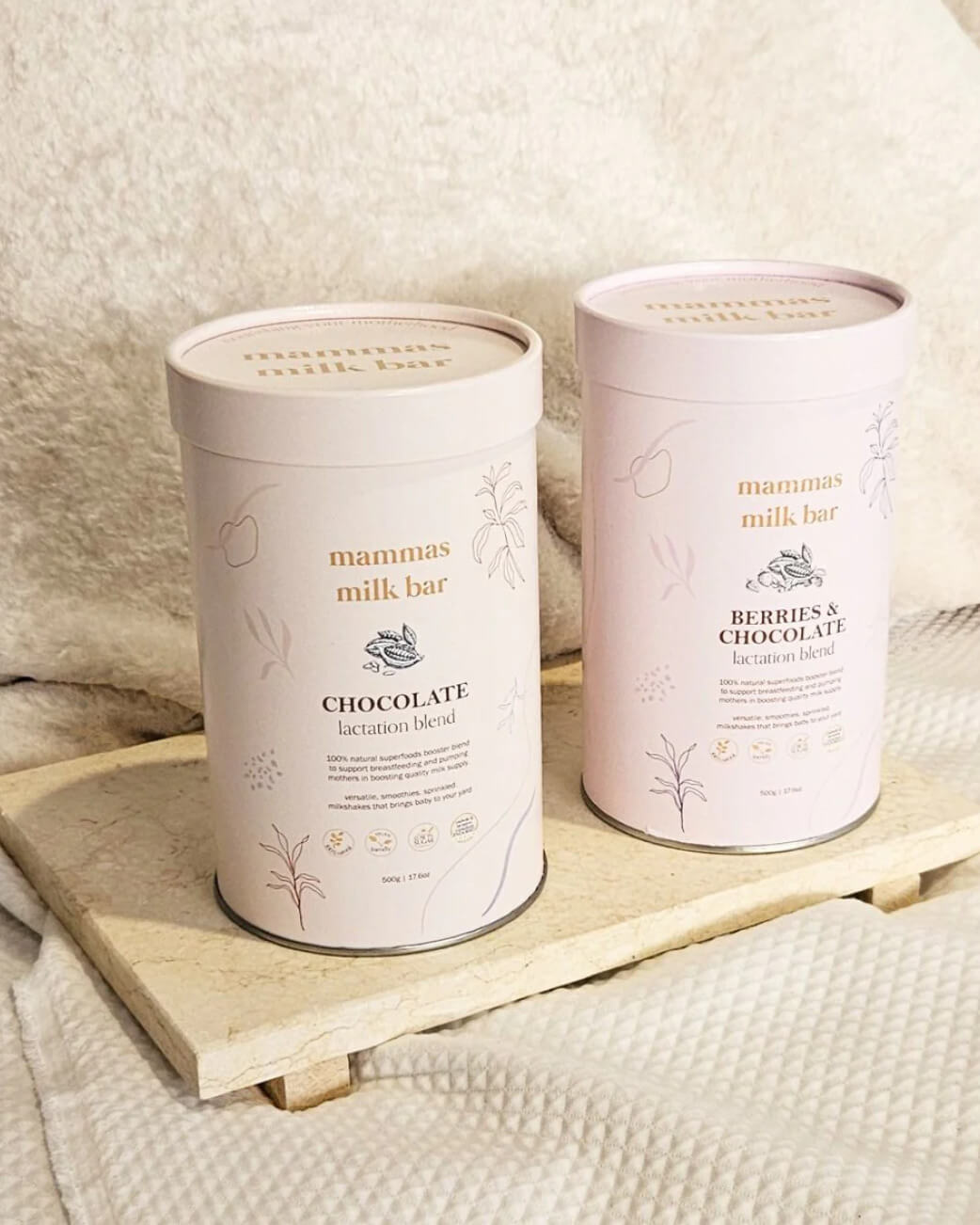 Two containers of 'mammas milk bar' on a wooden tray with a soft, neutral background.