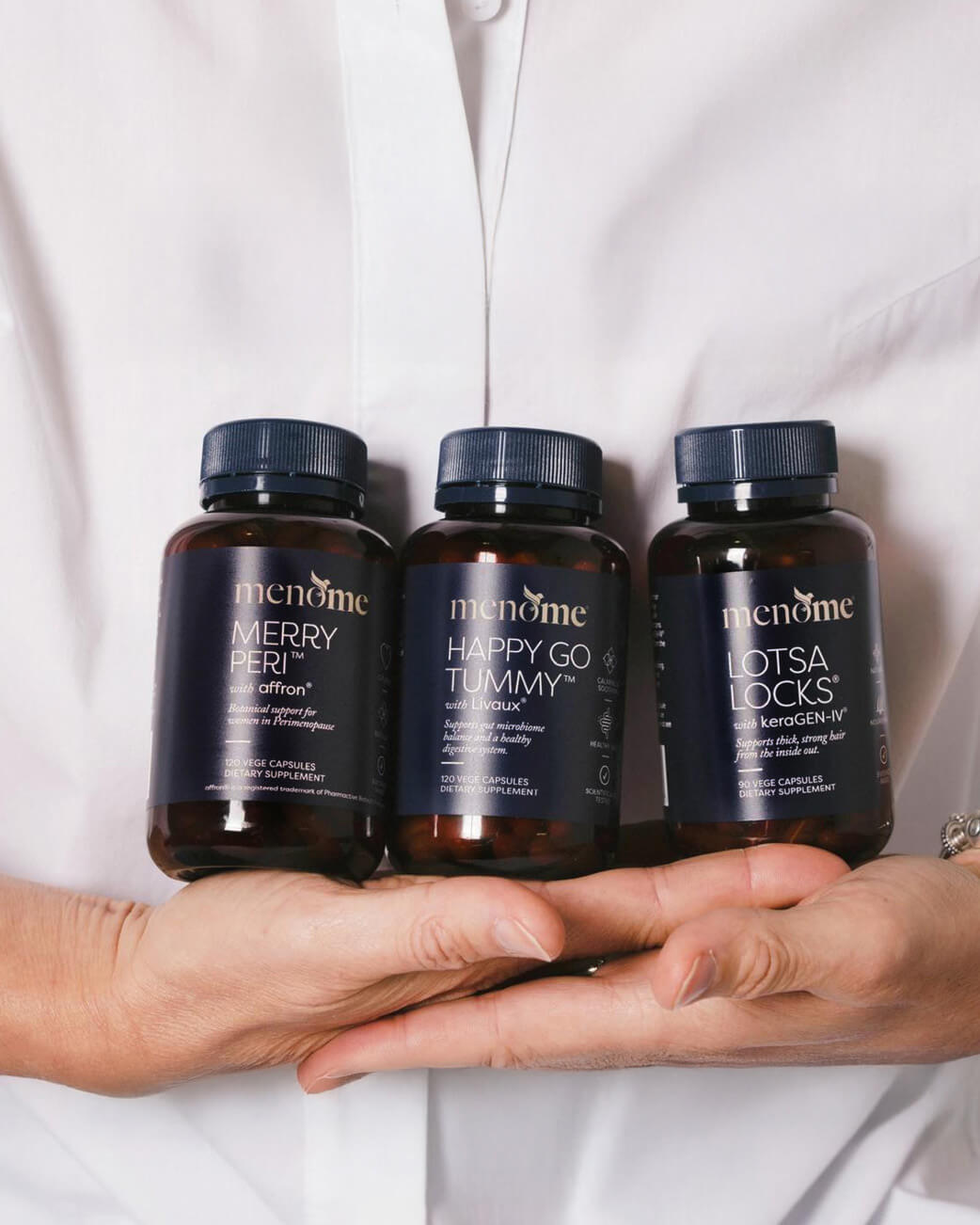 Three bottles of health supplements held by a person wearing a white coat.