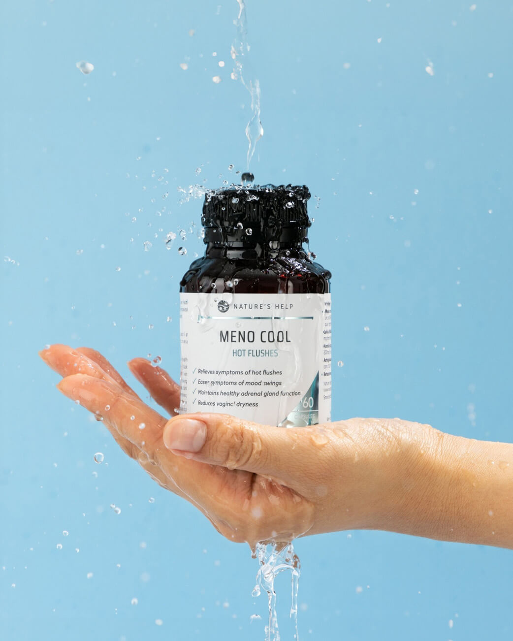 Hand holding a bottle labelled 'Meno Cool' against a blue background.