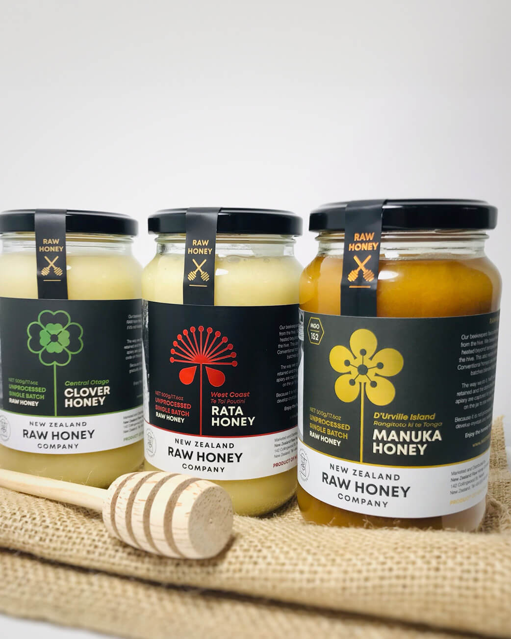 Four jars of raw honey on a white background.