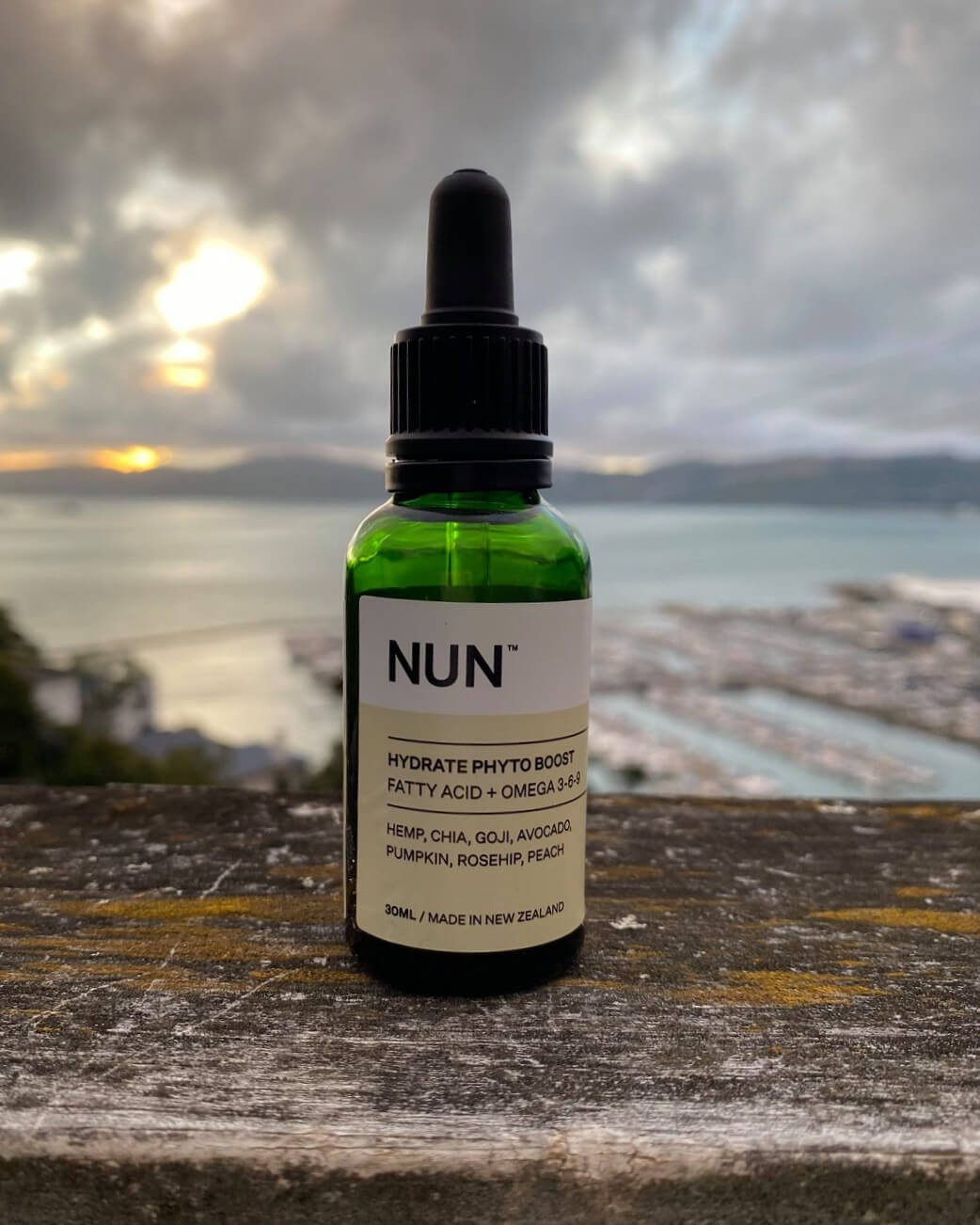 Bottle of NUN skincare product with a scenic background.