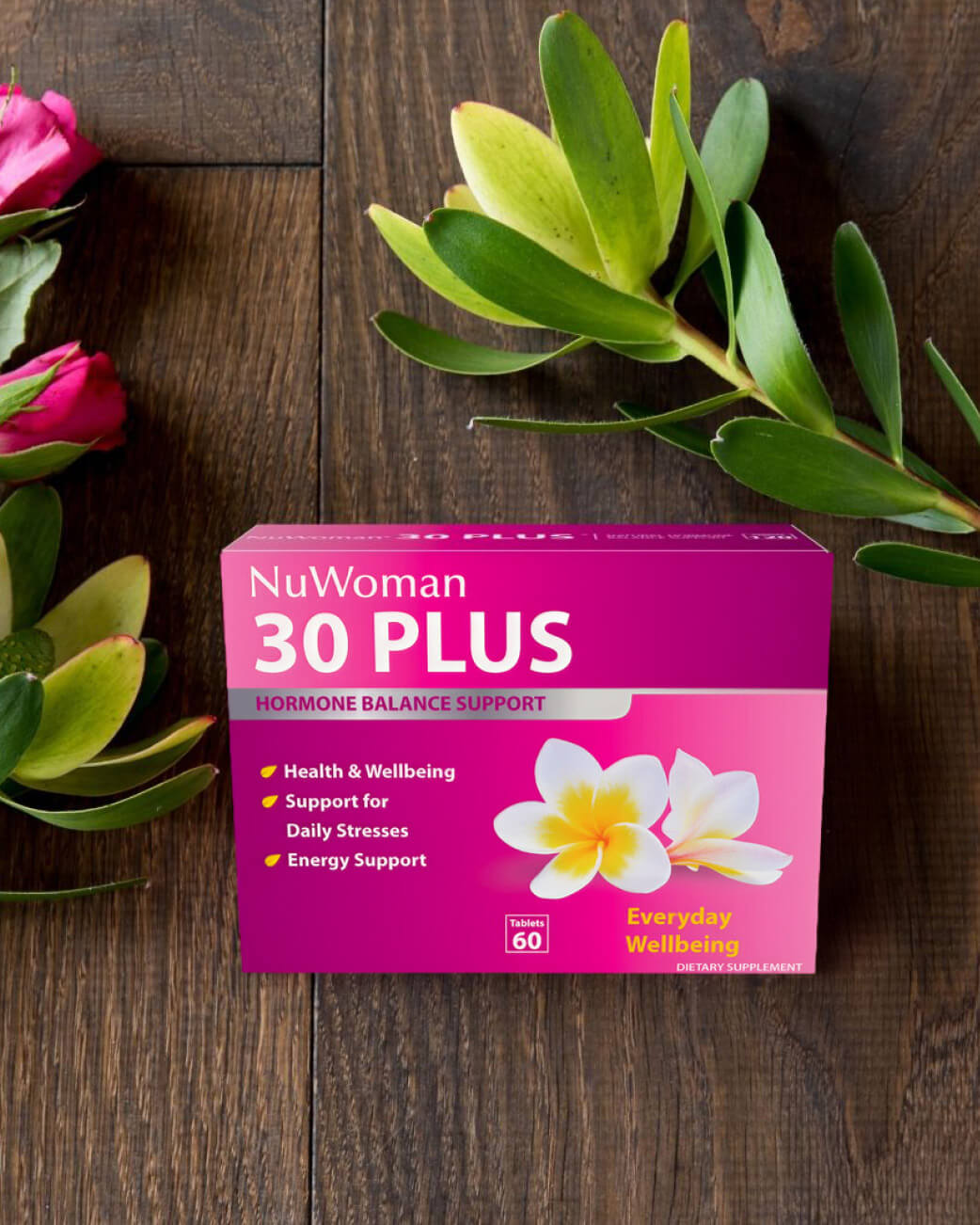 NuWoman 30 Plus supplement box on a wooden surface with flowers.
