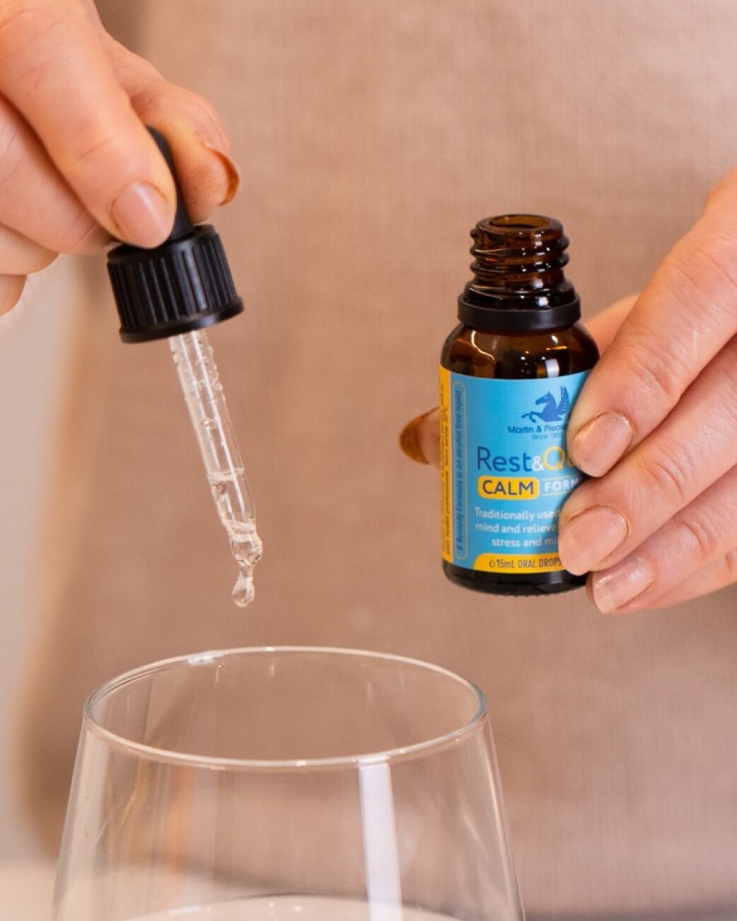 Bottle of Rest & Recover Calm Essential Oil with dropper and glass container on a beige background.