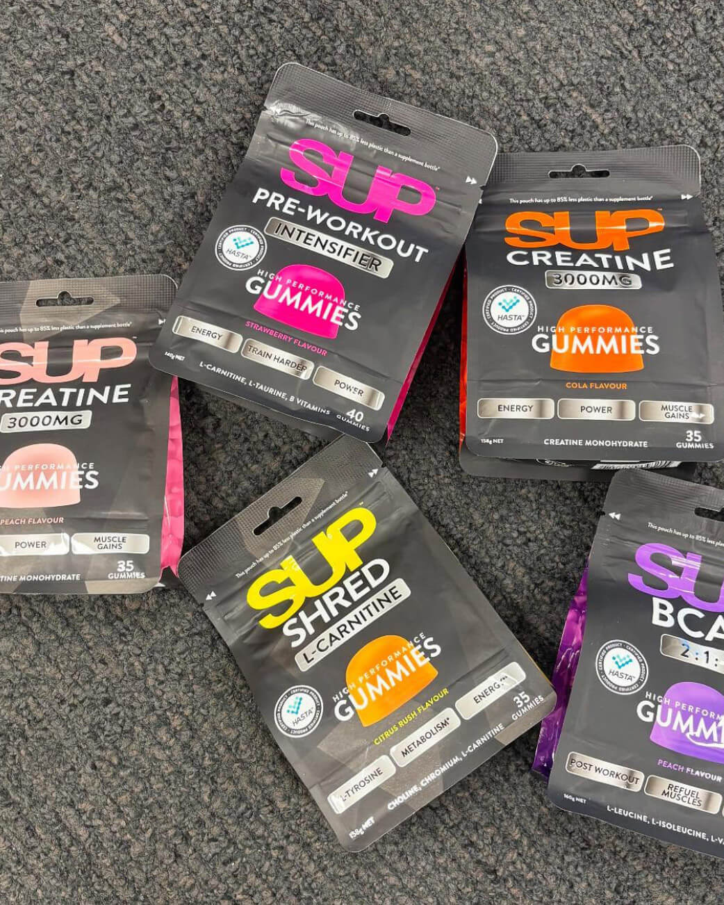 Supplement gummy packages from different brands on a grey surface.