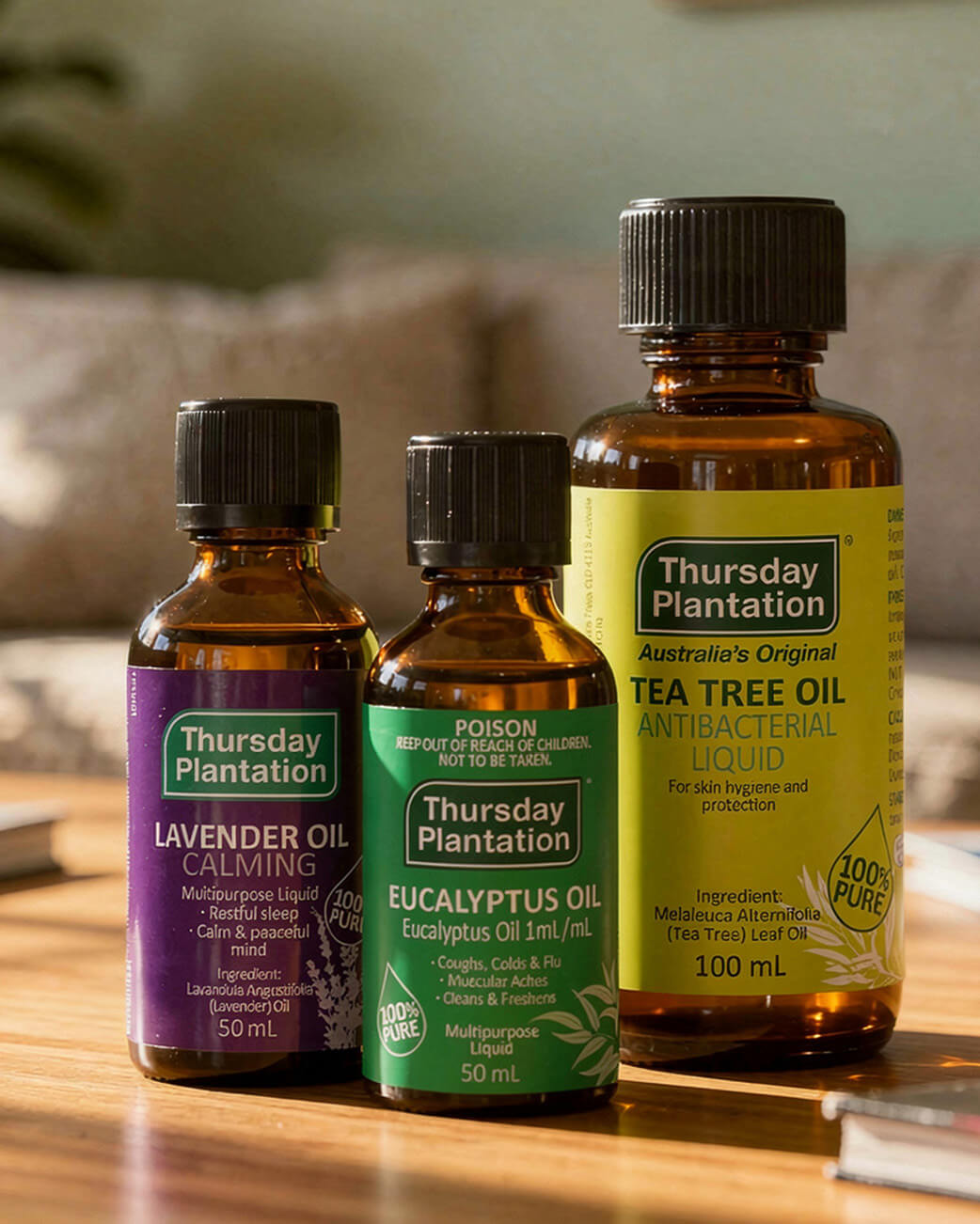 Three bottles of Thursday Plantation essential oils on a wooden surface.