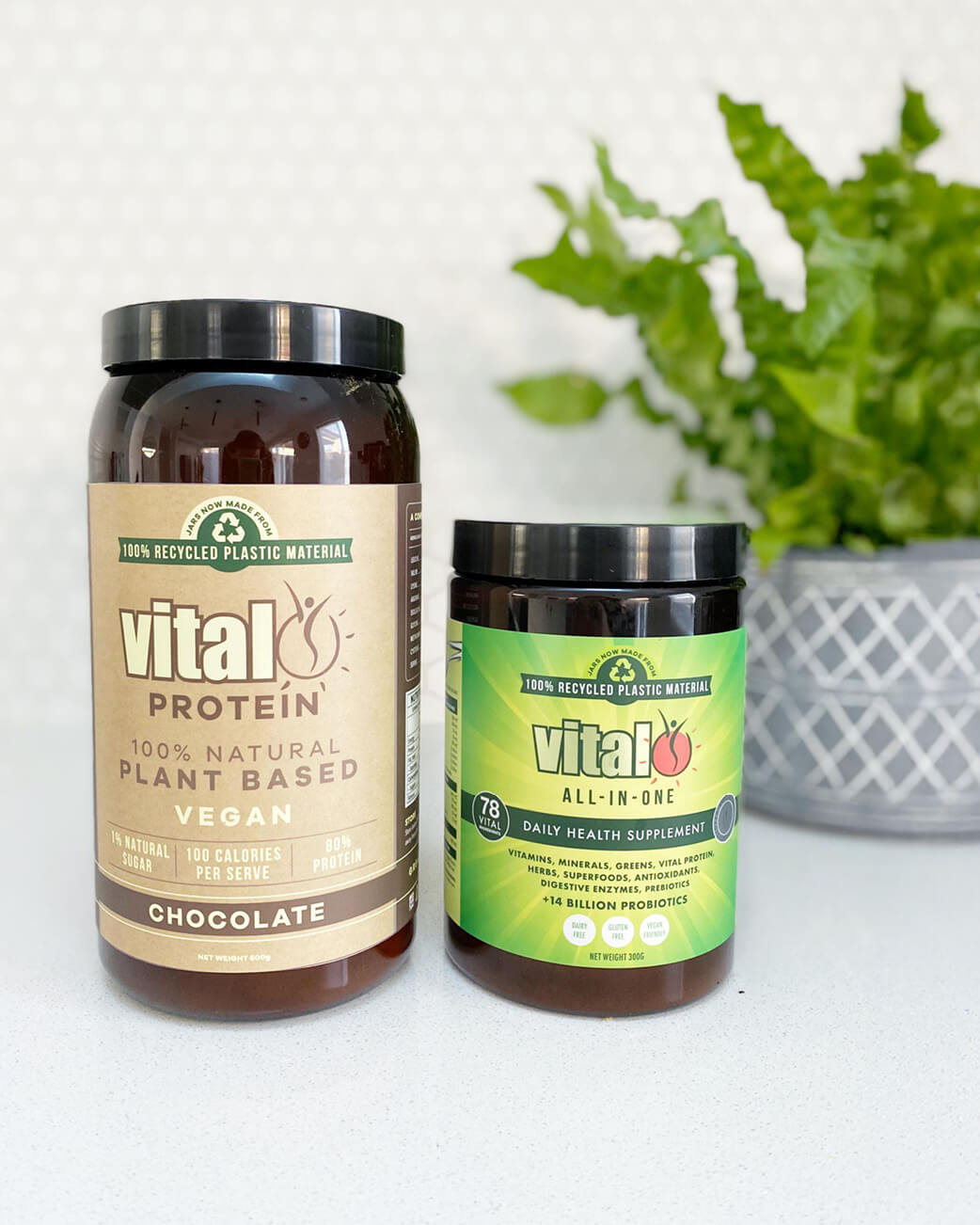 Two Vital Protein containers on a white surface with a plant in the background.