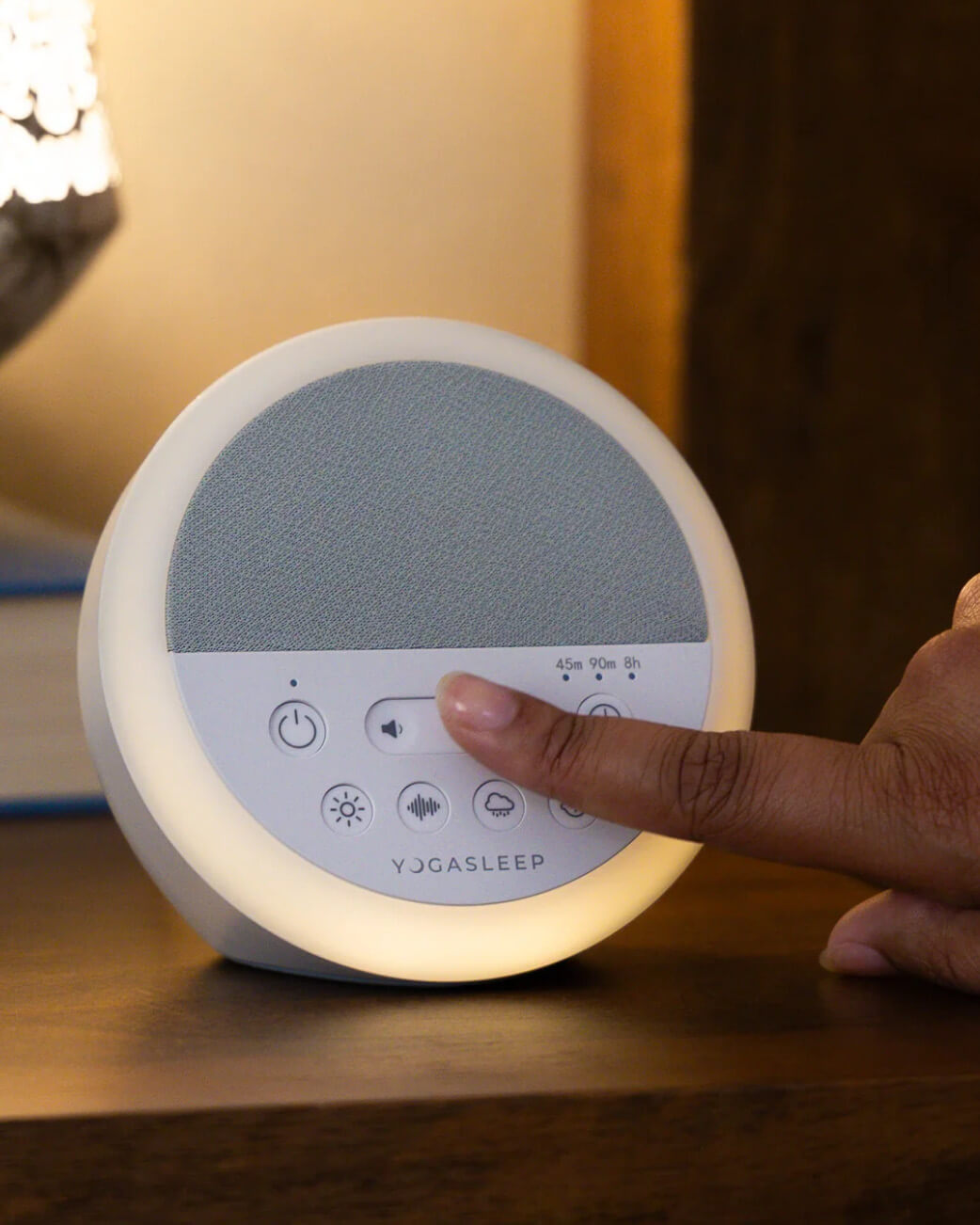 YogaSleep device being adjusted by a hand on a wooden surface.
