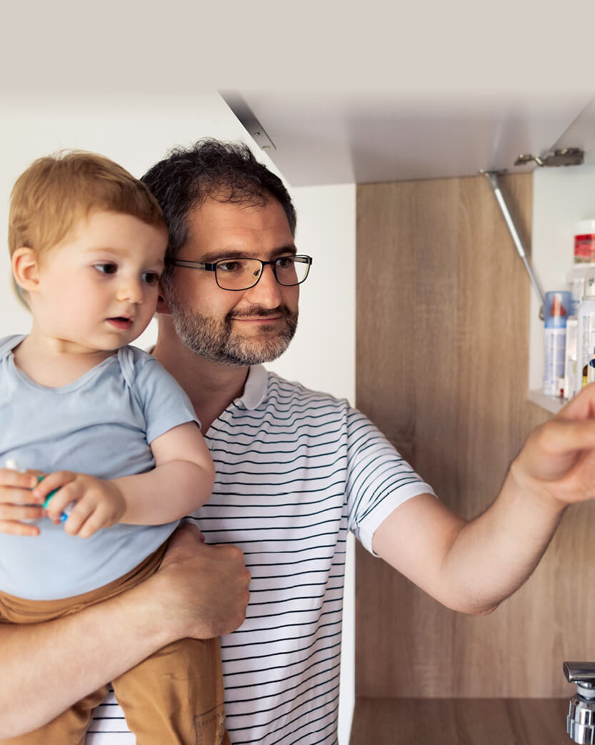 Man holding a child in a kitchen setting.