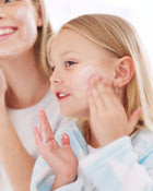 Woman and child applying cream to their faces against a white background.