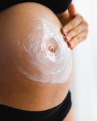 Close-up of a person applying cream to their stomach.