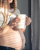 Person holding a white mug with a blurred background.