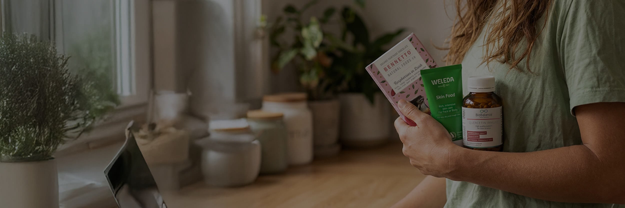 Person holding chocolate, moisturiser, and a supplement bottle.