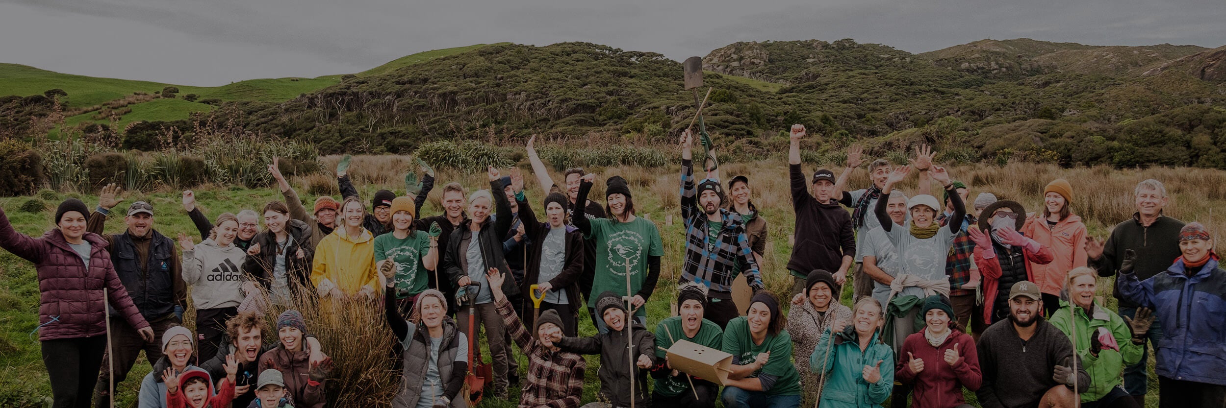 Volunteers outside planting trees and holding shovels.