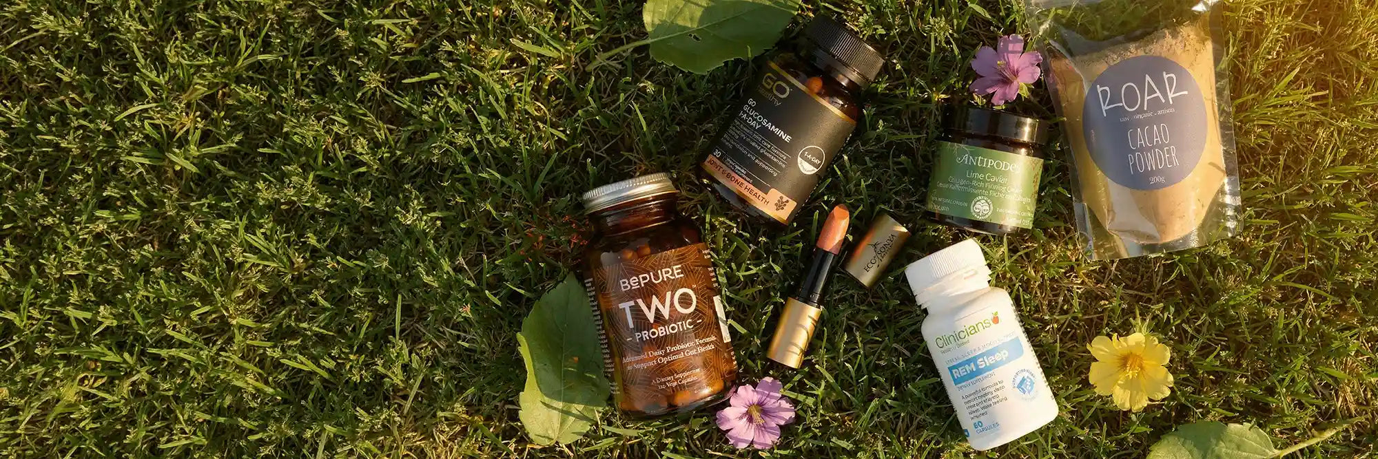 Collection of skincare and wellness products on a grassy background.