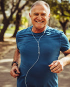 Man jogging outdoors with earphones, smiling.