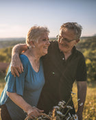 Senior couple standing in a field with a blurred background.