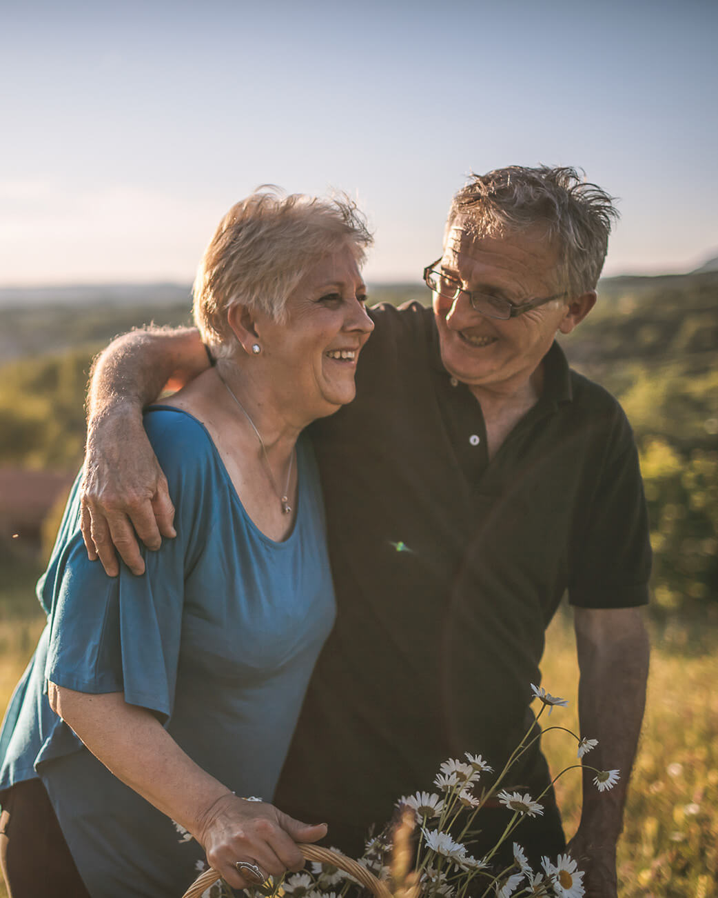 Senior couple standing in a field with a blurred background.