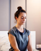 Woman sitting on a couch with a neutral expression indoors.