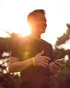 Man using a smartphone outdoors with a warm, blurred background.