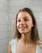 Woman smiling in a bathroom setting.