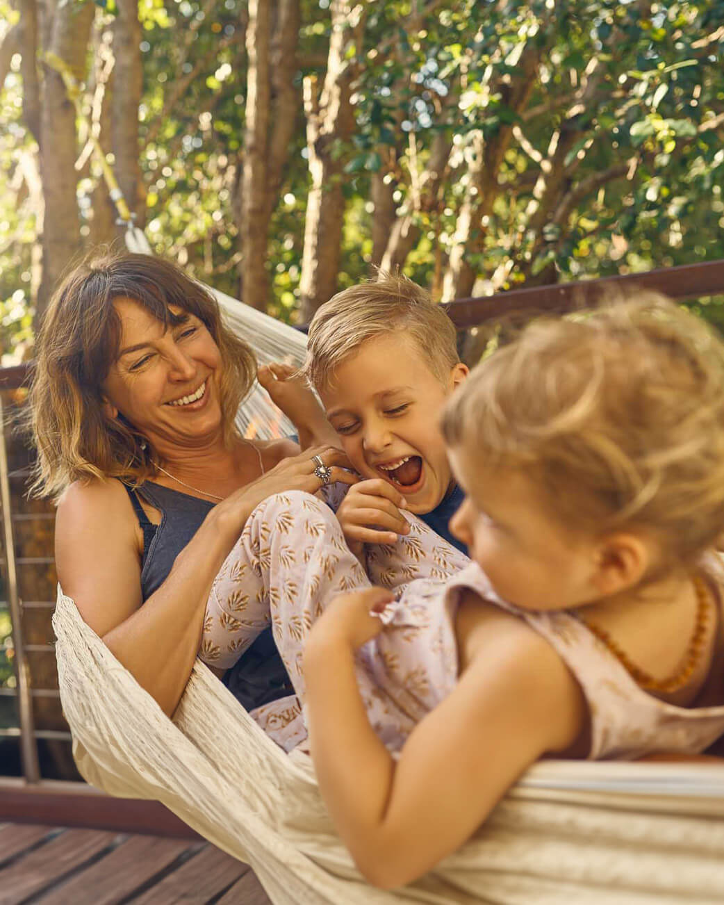 Mum and 2 kids in a hammock laughing.