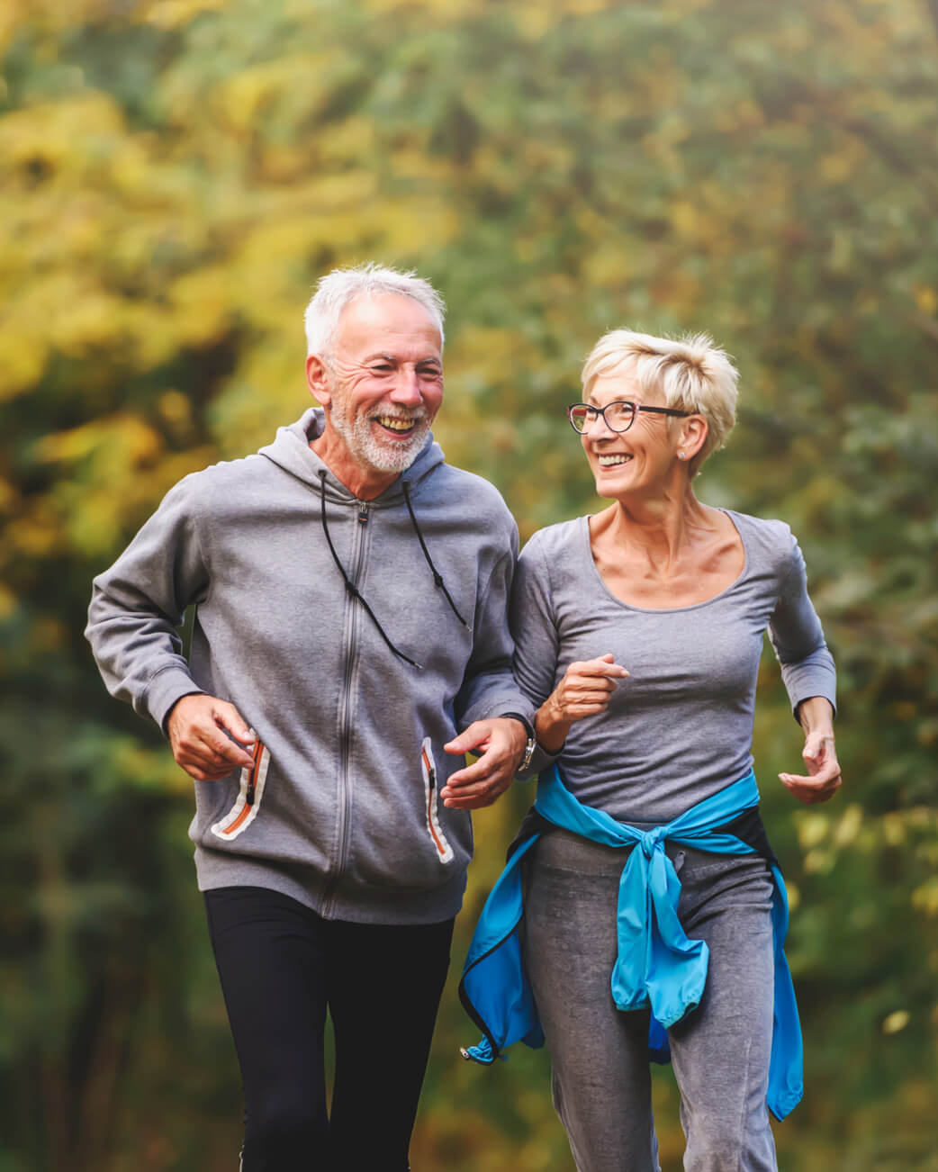 Older woman and man running in a natural setting.