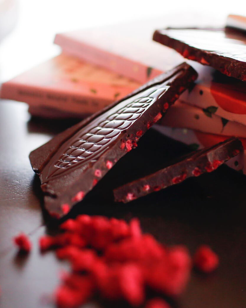Dark chocolate bar with red berries on a wooden surface