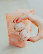 Hand holding two pink macaroons with a blurred background.