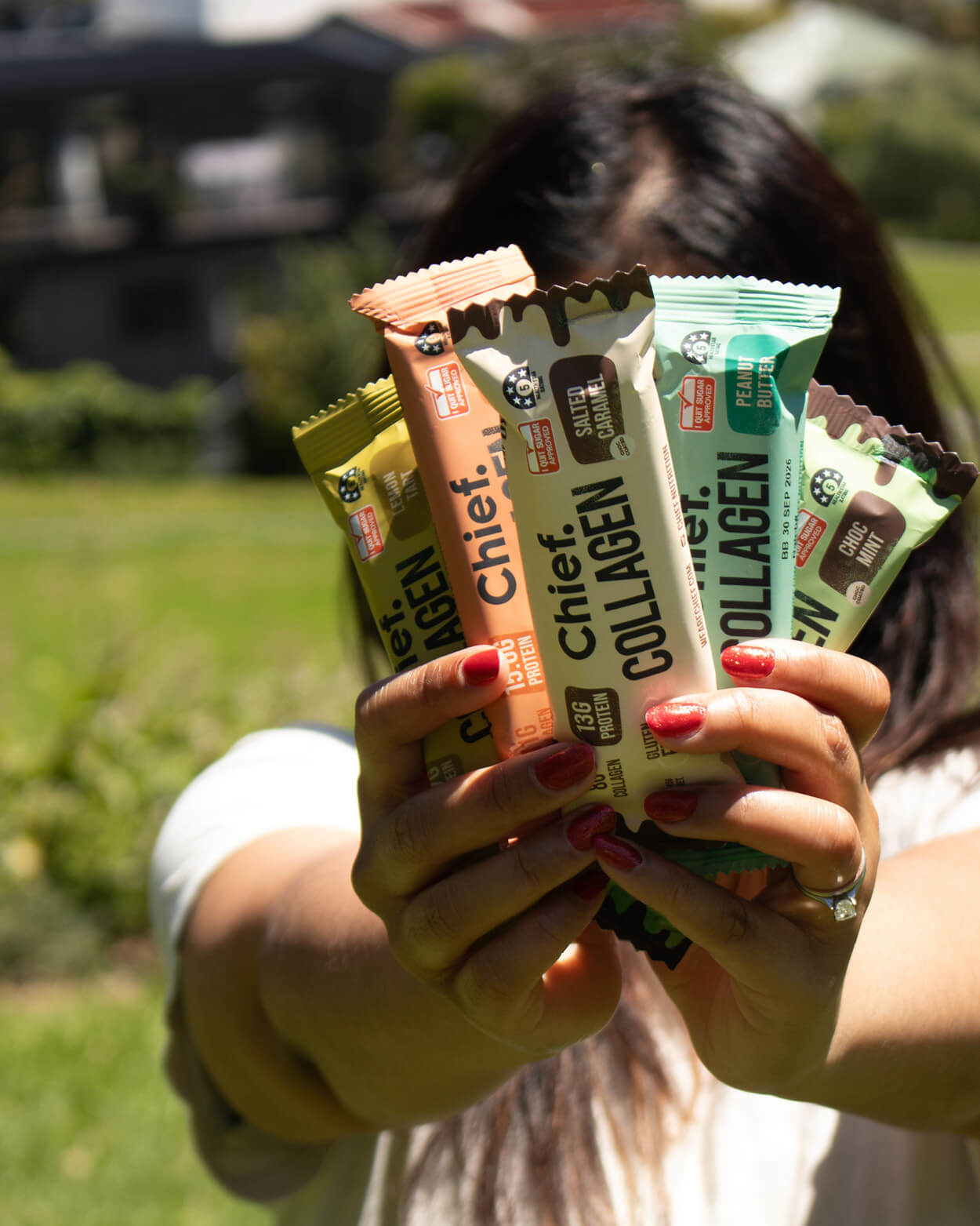 Person holding Chief Collagen Bars in an outdoor setting.