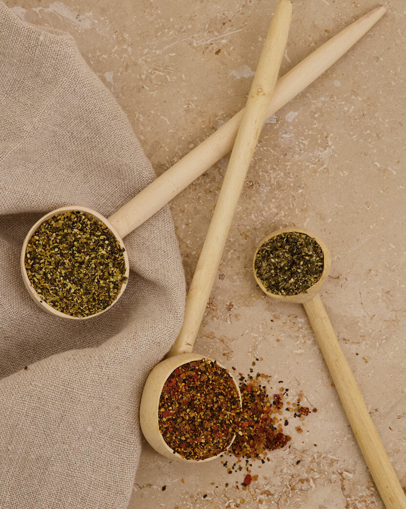 Wooden spoons with various spices on a textured surface