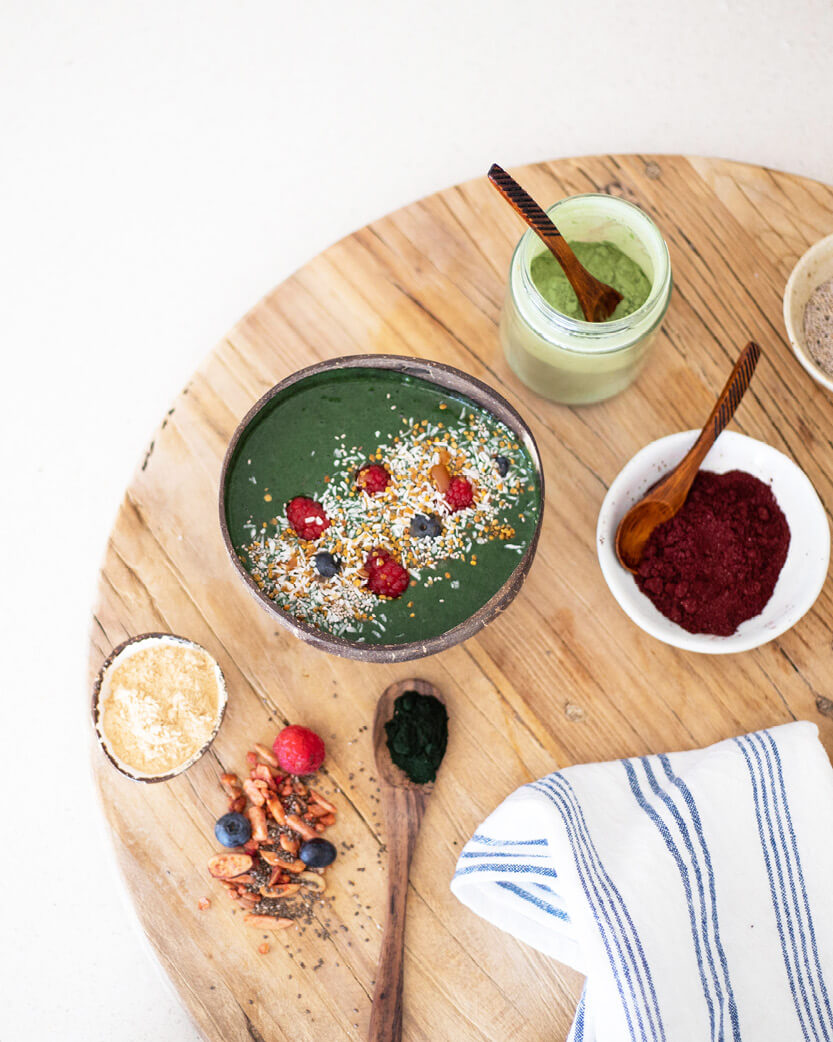 Green smoothie bowl with toppings on a wooden table