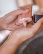 Person squeezing out foundation onto their hand.