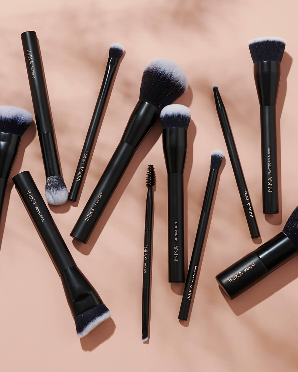 INIKA branded makeup brushes against a pink background.