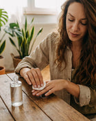 Woman with long brown hair removing nail polish with a cotton pad.
