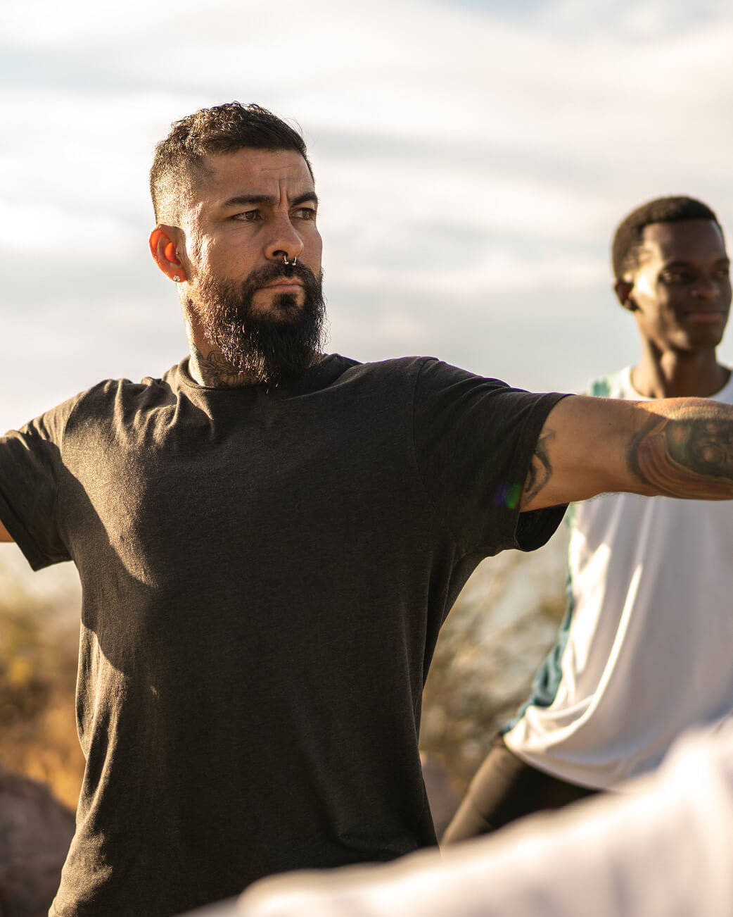 Man with a beard wearing a black shirt in a natural setting.