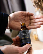 Bottle of BioBalance Argan Oil held by a person with another hand.