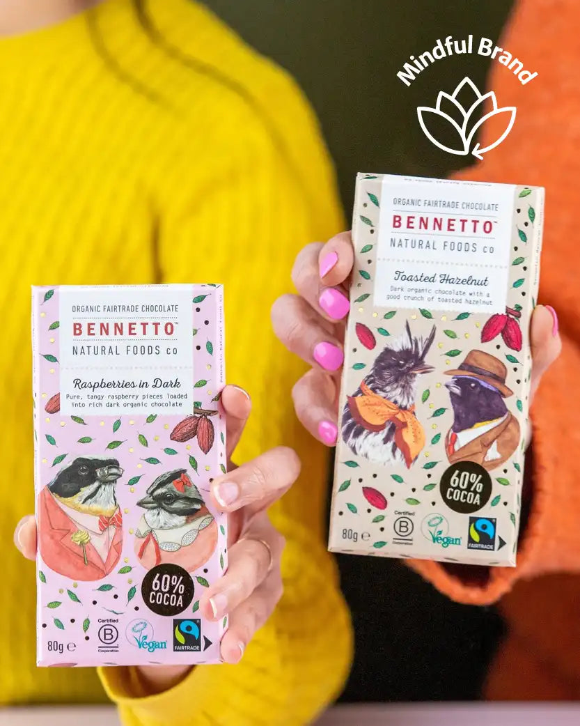 Two Bennetto chocolate bars held by a person wearing a yellow sweater, with the Mindful Brand logo above.