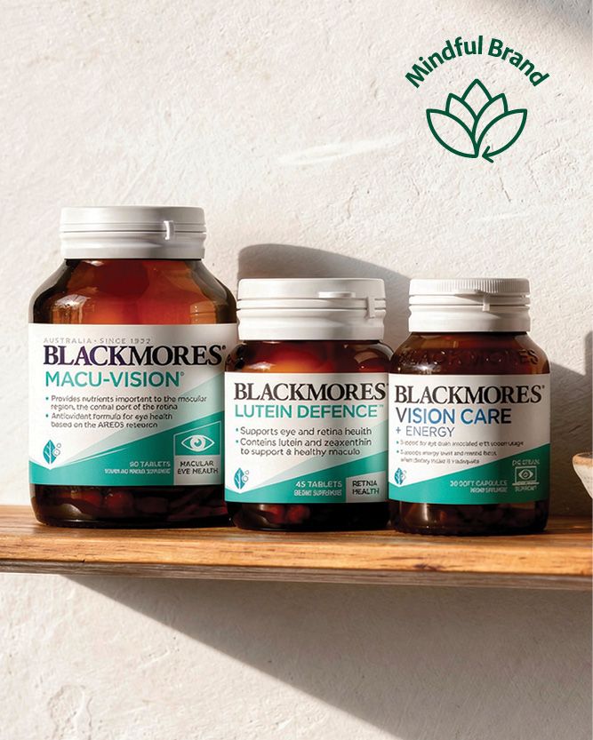 Three Blackmores supplement bottles arranged on a wooden shelf against a textured white wall. The bottles are amber brown with white caps and labels featuring teal and white sections.