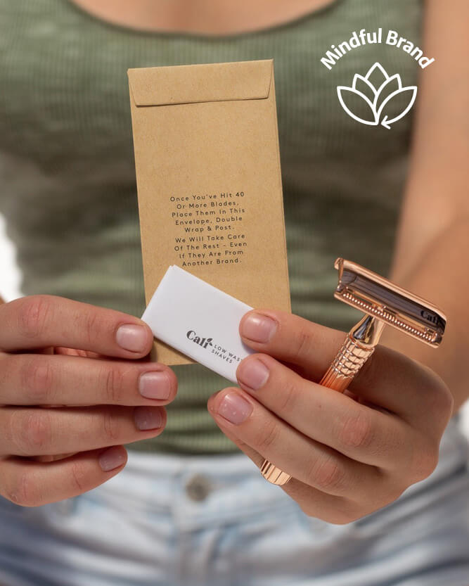Person holding a rose gold razor, white cartridge, and brown packaging with 'Mindful Brand' logo.
