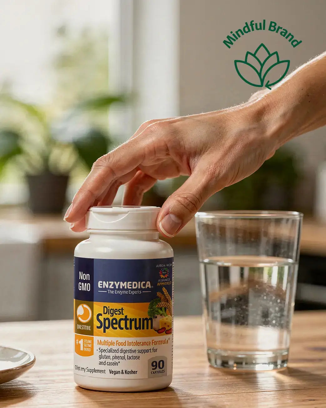 Person holding a supplement bottle labeled 'Enzymedica Digest Spectrum' with a glass of water on a table, featuring the 'Mindful Brand' logo.