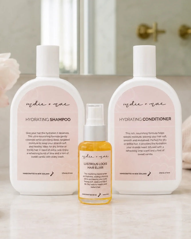 Indie + Mae's Hydrating Shampoo, Hydrating Conditioner & Hair Elixir bottles lined up in a bathroom.
